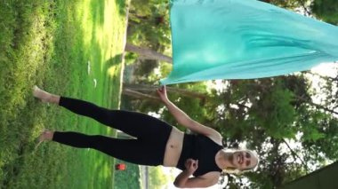 Kadınlar parkın dışında birlikte antrenman yapıyor. Yoga ve hamaklarda gerinme. Kadın sağlığı için spor. Egzersiz stresin azaltılmasına yardımcı olur, içindeki uyumu korur ve genel refaha katkıda bulunur.