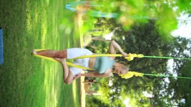 Yetişkin kadın, parkta hamakta aerobik yapıyor. Spor egzersizi meditasyon zen açık hava egzersizi. Kadın, vücut esnekliği için esniyor. Fiziksel ve duygusal refah için stresi azaltmak