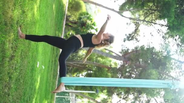Aero空中瑜伽教练向在吊床上做体操的妇女解释和帮助她们如何进行安全和健康的锻炼 在公园里呼吸新鲜空气 女子伸展运动 — 图库视频影像