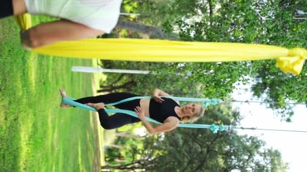 成年女子在公园的吊床上练习瑜伽 户外运动锻炼 女性伸展身体以获得身体的灵活性 舒缓压力能增强肌肉的身心健康 — 图库视频影像