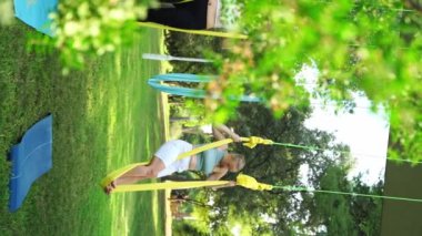Yetişkin kadın, parkta hamakta aerobik yapıyor. Spor egzersizi meditasyon zen açık hava egzersizi. Kadın, vücut esnekliği için esniyor. Fiziksel ve duygusal refah için stresi azaltmak