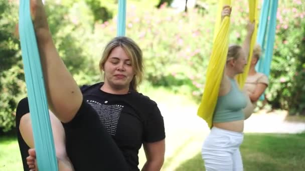 屋外ハンモックでエアロヨガをする女性は アサナを練習します パブリックパークで瞑想と禅の練習 大人のためのメンタルヘルス 女性のためのアクティブな健康的なライフスタイル — ストック動画