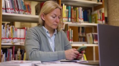 Uzaktan kumandalı orta yaşlı kadın Laptop ofis yöneticisini kullanıyor, cep telefonu kullanıyor, çevrimiçi mesajlaşıyor, arıyor. Uzaktan kumandalı dijital göçebe konferansı. Çevrimiçi danışma istemcisi