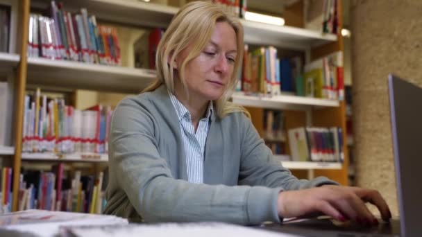 中年妇女科学家在高校图书馆撰写论文大学生自由职业者用笔记本电脑在键盘上用电子邮件打字提高职业资格 — 图库视频影像