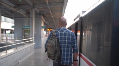 Orta yaşlı bir adam demiryolu platformunda yürüyor. Dikiz aynası. Toplu taşıma yolcusu metroya biner. Banliyö sakini işe gidiyor. Sırt çantalı adam metro kullanıyor. Toplu taşımacılıkta yetişkin.