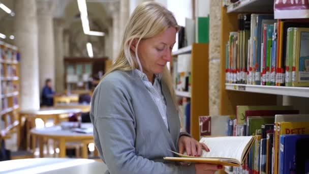 Женщина Средних Лет Библиотеке Книжном Магазине Выбирает Книгу Взрослые Перелистывают — стоковое видео