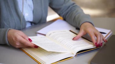 Kitap okuyan orta yaşlı kadın bilim adamı üniversite kütüphanesinde tez yazıyor. Yetişkin öğrenci, üniversite öğrencisiyle birlikte mesleki yeterliliği yükseltme konusunda serbest çalışıyor.