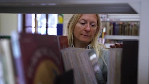 Жінка Середнього Віку Бібліотеці Або Книгарні Вибирає Книгу Дорослі Перевертаються — стокове відео
