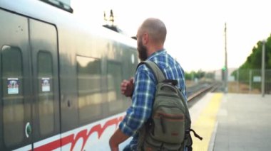 Sırt çantalı şehir sakini platformda metro trenini bekliyor. İşe giden bir yetişkin, toplu taşıma araçlarında cep telefonu kullanıyor. Sabahları şehir hayatı metroya dayanır.