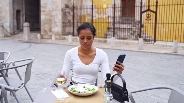 グリーンサラダを食べて携帯電話を使用する女性のクローズアップ手 健康的な食べ物 不健康な習慣 中毒インターネット ブロガーの後 電子ブック 雑誌を読み 映画を見る — ストック動画