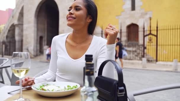スペインの若い女性フード愛好家は レストランの屋外テーブルで食事を楽しんでいます ビーガンはグリーンサラダを食べる 健康的な日常生活を送っています カフェテリアテラスで美しいラテンアメリカの女性 — ストック動画