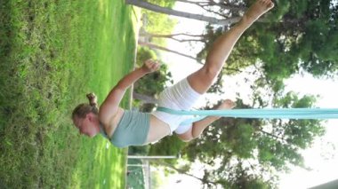 Kadınlar parkın dışında birlikte antrenman yapıyor. Yoga ve hamaklarda gerinme. Kadın sağlığı için spor. Egzersiz stresin azaltılmasına yardımcı olur, içindeki uyumu korur ve genel refaha katkıda bulunur.