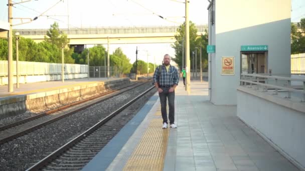 城里人背着背包在月台上等地铁列车 一个在公共交通工具上使用手机上班的成年人 早上的城市生活就像市民依赖地铁一样 — 图库视频影像