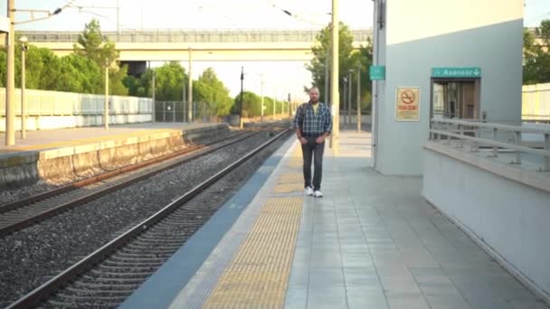 城里人背着背包在月台上沿着地铁走着 一个在公共交通工具上使用手机上班的成年人 早上的城市生活就像市民依赖地铁一样 — 图库视频影像