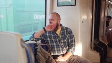 Yorgun adam esniyor, işten metroya biniyor. Banliyö sakini sabah erken saatlerde toplu taşıma araçlarıyla işe gider. Sırt çantalı adam metro kullanıyor. Toplu taşımacılıkta yetişkin.