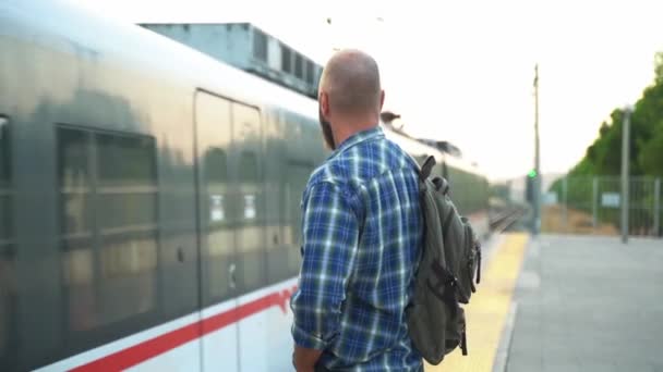 鉄道プラットフォームの地下鉄を待っているバックパックを持つ男 大人は公共交通機関でガジェットスマートフォンを使用して動作します 朝から地下鉄を使った都市生活 輸送における習慣の概念 — ストック動画