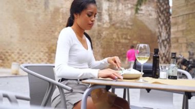 İspanyol genç kadın yemek aşığı açık hava restoranında yemeğin tadını çıkarıyor. Vejetaryen yemeği yeşil salata yer. Günlük mutlu sağlıklı alışkanlıklar. Kafeterya terasında güzel bir Latin Amerikalı kadın.