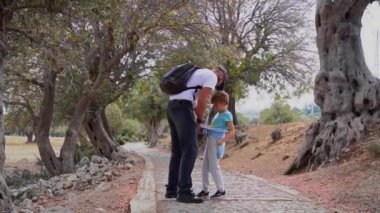 İnsanlarla seyahat et. Kafkas babası ve kızı antik orman parkında yaz mevsiminde birlikte yürürler. Çocuk mutlu bir şekilde atladı. Aile birlikte boş zaman aktiviteleri.