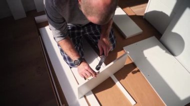 Kafkasyalı adam mobilya montajı, gardırop, çivi ve tornavida vidaları yapıyor. Yetişkin bir zanaatkar ev tamiri yapar.