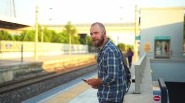 Sırt çantalı şehir sakini platformda metro trenini bekliyor. İşe giden bir yetişkin, toplu taşıma araçlarında cep telefonu kullanıyor. Sabahları şehir hayatı metroya dayanır.