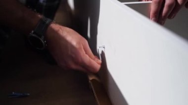 Kafkasyalı adam mobilya montajı, gardırop, çivi ve tornavida vidaları yapıyor. Yetişkin bir zanaatkar ev tamiri yapar.