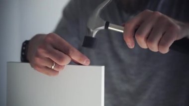 Kafkasyalı adam mobilya montajı, gardırop, çivi ve tornavida vidaları yapıyor. Yetişkin bir zanaatkar ev tamiri yapar.