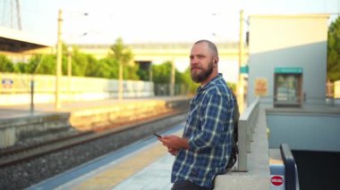 Sırt çantalı bir adam tren istasyonunda metro trenini bekliyor. Yetişkinler toplu taşıma araçlarında akıllı telefonlar kullanırlar. Sabahları metroyu kullanan bir şehir vatandaşı. Ulaşımda alışkanlık kavramı