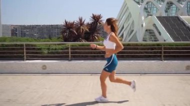 Asyalı yetişkin kadın koşucu spor kıyafetleriyle koşuyor güneşli bir sabah kentsel yüksek teknoloji şehir fütüristik geçmişi var. Koşu maratonu, dayanıklılık, kalp egzersizi sağlıklı yaşam tarzı.