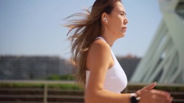 Asyalı yetişkin kadın koşucu spor kıyafetleriyle koşuyor güneşli bir sabah kentsel yüksek teknoloji şehir fütüristik geçmişi var. Koşu maratonu, dayanıklılık, kalp egzersizi sağlıklı yaşam tarzı.