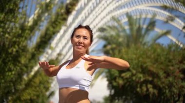 Asyalı yetişkin kadın sporcu kıyafetleriyle koşuyor. Güneşli sabah antrenmanlarından önce kas ve eklemlerini ısıtıyor. Palm City 'nin gelecekteki koşu bandı. Yetişkinler için kentsel sağlıklı yaşam tarzı