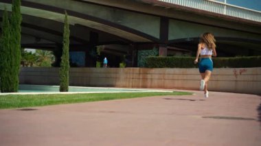 Asyalı yetişkin kadın koşucu spor kıyafetleriyle koşuyor güneşli bir sabah uykusunda yüksek teknoloji şehir arka planında. Koşu maratonu, dayanıklılık, kalp egzersizi sağlıklı yaşam tarzı.