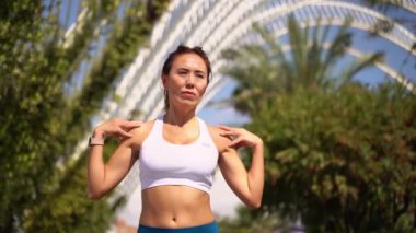 Asyalı yetişkin kadın sporcu kıyafetleriyle koşuyor. Güneşli sabah antrenmanlarından önce kas ve eklemlerini ısıtıyor. Palm City 'nin gelecekteki koşu bandı. Yetişkinler için kentsel sağlıklı yaşam tarzı