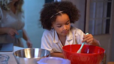 Modern mutfak akşamında melez ırk kızlarına krep ve sağlıklı yemek yapmayı öğreten mutlu bir çift. Gülümseyen, çok ırklı bir aile şirin, küçük, çeşitli çocuklarla hazırlanıyor.