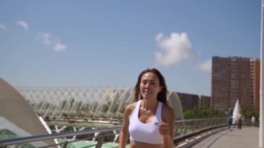Spor kıyafetleriyle koşan Asyalı yetişkin kadın koşucu güneşli bir sabah kentsel yüksek teknoloji fütürist şehir geçmişi. Koşu maratonu, dayanıklılık, kalp egzersizi sağlıklı yaşam tarzı.