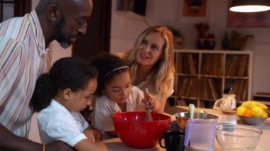 Modern mutfak akşamında melez küçük ırk kızlarına krep pişirme, hamur ve sağlıklı yemekleri öğretmekten mutlu oluruz. Gülümseyen çok ırklı aile hazırlanıyor.
