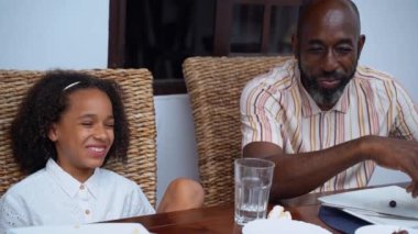 Afro-Amerikan beyaz aileler ve çocuklar hafta sonu birlikte öğle yemeği kahvaltısı yiyor. Aile geleneği, çocuklar için sağlıklı yiyecekler, boş zaman aktivitesi, bakım ve ilişkiler