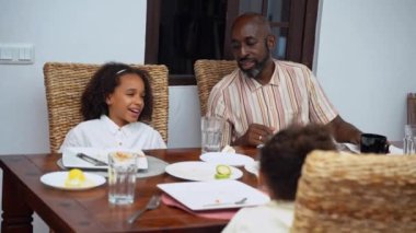 Afro-Amerikan beyaz aileler ve çocuklar hafta sonu birlikte öğle yemeği kahvaltısı yiyor. Aile geleneği, çocuklar için sağlıklı yiyecekler, boş zaman aktivitesi, bakım ve ilişkiler