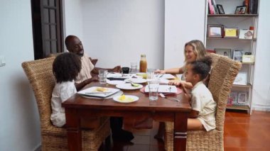 Afro-Amerikan beyaz aileler ve çocuklar hafta sonu birlikte öğle yemeği kahvaltısı yiyor. Aile geleneği, çocuklar için sağlıklı yiyecekler, boş zaman aktivitesi, bakım ve ilişkiler