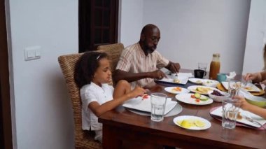 Afro-Amerikan beyaz aileler ve çocuklar hafta sonu birlikte öğle yemeği kahvaltısı yiyor. Aile geleneği, çocuklar için sağlıklı yiyecekler, boş zaman aktivitesi, bakım ve ilişkiler