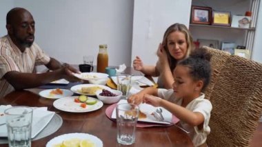 Afro-Amerikan beyaz aileler ve çocuklar hafta sonu birlikte öğle yemeği kahvaltısı yiyor. Aile geleneği, çocuklar için sağlıklı yiyecekler, boş zaman aktivitesi, bakım ve ilişkiler