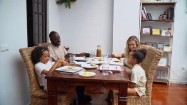 Afro-Amerikan beyaz aileler ve çocuklar hafta sonu birlikte öğle yemeği kahvaltısı yiyor. Aile geleneği, çocuklar için sağlıklı yiyecekler, boş zaman aktivitesi, bakım ve ilişkiler