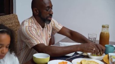 Afro-Amerikan beyaz aileler ve çocuklar hafta sonu birlikte öğle yemeği kahvaltısı yiyor. Aile geleneği, çocuklar için sağlıklı yiyecekler, boş zaman aktivitesi, bakım ve ilişkiler