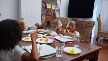 Afro-Amerikan beyaz aileler ve çocuklar hafta sonu birlikte öğle yemeği kahvaltısı yiyor. Aile geleneği, çocuklar için sağlıklı yiyecekler, boş zaman aktivitesi, bakım ve ilişkiler