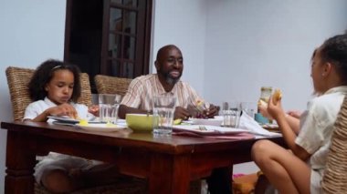 Afro-Amerikan beyaz aileler ve çocuklar hafta sonu birlikte öğle yemeği kahvaltısı yiyor. Aile geleneği, çocuklar için sağlıklı yiyecekler, boş zaman aktivitesi, bakım ve ilişkiler