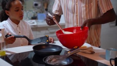 Afrikalı Amerikalı baba kızıyla birlikte krep kızartıyor. Günlük aile rutini, yaygın alışkanlıklar, akşam yemeği için sağlıklı yemekler, baba ve çocuk aktif yaşam tarzı.