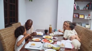 Afro-Amerikan beyaz aileler ve çocuklar hafta sonu birlikte öğle yemeği kahvaltısı yiyor. Aile geleneği, çocuklar için sağlıklı yiyecekler, boş zaman aktivitesi, bakım ve ilişkiler