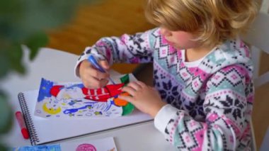 Noel Baba 'ya yeni yıl tatili için mektup yazan çocuk, rahat Noel süslemeleri ve ışıkları, renkli kalemler çizen kız, Noel Baba' ya hediyeler hazırlayan çocuk,