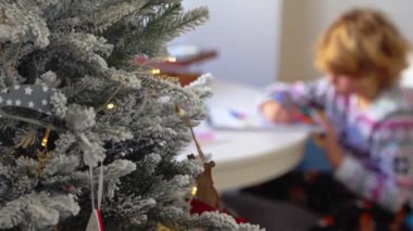 Noel Baba 'ya yeni yıl tatili için mektup yazan çocuk, rahat Noel süslemeleri ve ışıkları, renkli kalemler çizen kız, Noel Baba' ya hediyeler hazırlayan çocuk,