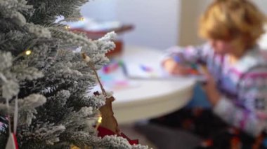 Noel Baba 'ya yeni yıl tatili için mektup yazan çocuk, rahat Noel süslemeleri ve ışıkları, renkli kalemler çizen kız, Noel Baba' ya hediyeler hazırlayan çocuk,