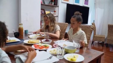 Afro-Amerikan beyaz aileler ve çocuklar hafta sonu birlikte öğle yemeği kahvaltısı yiyor. Aile geleneği, çocuklar için sağlıklı yiyecekler, boş zaman aktivitesi, bakım ve ilişkiler